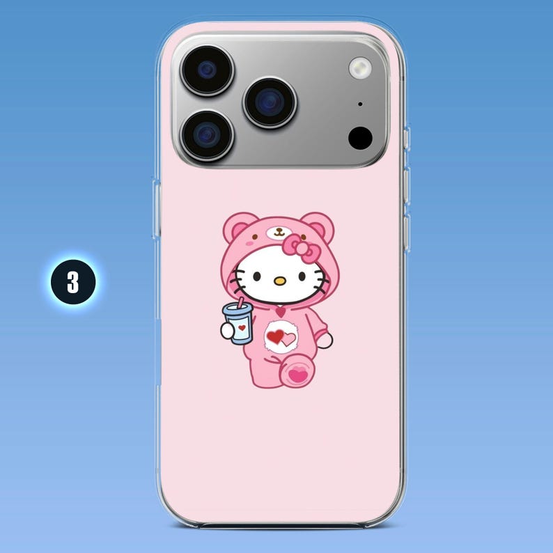 Puede incluir: Una funda de smartphone rosa claro con un gr&aacute;fico de un personaje de gato blanco que lleva una capucha de oso rosa y sostiene una bebida azul. El personaje tiene un lazo rosa, bigotes negros y un emblema de coraz&oacute;n en el pecho. El n&uacute;mero 3 es visible.