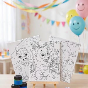 Könnte beinhalten: Drei rechteckige Leinwände mit schwarz-weißen Strichzeichnungen eines Hundes, eines Pandas, der Bambus frisst, und eines Hais. Das Set enthält kleine Farbtöpfe, eine weiße Kunststoff-Farbpalette und zwei Pinsel auf einer hölzernen Staffelei.