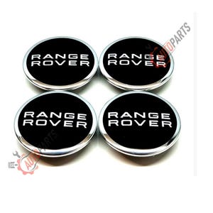 May include: Four black and silver Range Rover wheel center caps. Each cap has a black center with the words "RANGE ROVER" in white lettering. The caps have a silver border.
