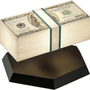May include: A bundle of hundred-dollar bills, secured with a green and white band, sits on a black, geometric base. The bills feature Benjamin Franklin's portrait and the text "100". The base has a dark, reflective surface.