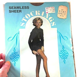 Puede incluir: Paquete vintage de medias transparentes sin costuras. El paquete es azul claro con la palabra "STOCKINGS" en un diseño circular. El paquete también tiene las palabras "SEAMLESS SHEER" en la parte superior. Una mujer con un atuendo negro aparece en el paquete.