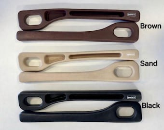Pode incluir: Quatro puxadores de plástico em castanho, areia e preto. Cada puxador tem um design curvo com uma grande abertura oval e uma abertura retangular menor. A palavra "qorex" é impressa em cada puxador.