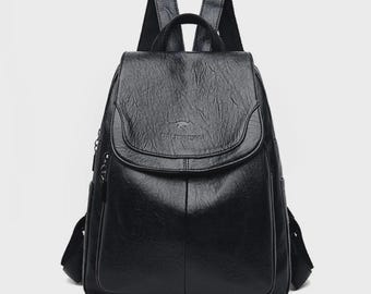 Pode incluir: Mochila preta com fecho de aba e alças ajustáveis. A bolsa tem uma aparência texturizada e um pequeno logotipo na frente. Possui uma alça superior e bolsos laterais.