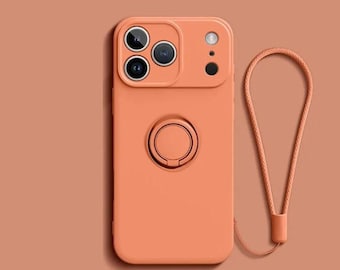 Pode incluir: Uma capa de telefone cor de pêssego com um módulo de câmera, suporte de anel e uma pulseira de pulso combinando. A capa tem um acabamento liso e foi projetada para proteger o telefone. A pulseira é em laço e presa na parte inferior da capa.