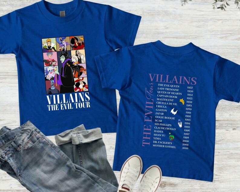Op de afbeelding: Twee koningsblauwe t-shirts met de tekst "VILLAINS THE EVIL TOUR". E&eacute;n shirt heeft een collage van schurkenpersonages. Het andere shirt geeft schurken en hun debuutjaren weer. Een spijkerbroek en witte sneakers staan ook op de afbeelding.