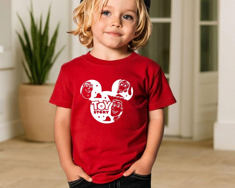 K&ouml;nnte beinhalten: Ein rotes T-Shirt mit einem wei&szlig;en Aufdruck des Toy Story-Logos und Charaktergesichtern. Das kurz&auml;rmelige Shirt besteht aus einem weichen Material. Das Design zeigt die Gesichter von Woody, Buzz Lightyear und anderen Charakteren.