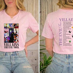 Op de afbeelding: Lichtroze T-shirt met een afbeelding van tekenfilm-schurken en de tekst "VILLAINS THE EVIL TOUR". De achterkant van het shirt geeft de schurken en hun jaren weer.