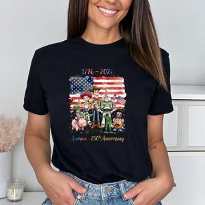 May include: Black t-shirt featuring a graphic of the American flag with the text "1776-2026" and a group of cartoon characters. The text "America - 250th Anniversary" is below the characters.