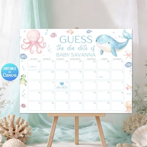 以下が含まれることがあります： 「GUESS the due date of BABY SAVANNA」の文字が入ったベビーシャワーカレンダー。タコ、クジラ、その他の海の生き物のイラストが特徴です。カレンダーは木製のイーゼルに表示されています。