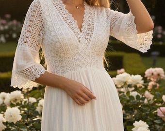 May include: A white floor-length dress featuring a V-neckline, intricate lace detailing on the bodice and sleeves, and three-quarter length bell sleeves. The garment includes a fitted waist section and a tiered skirt with lace panels.