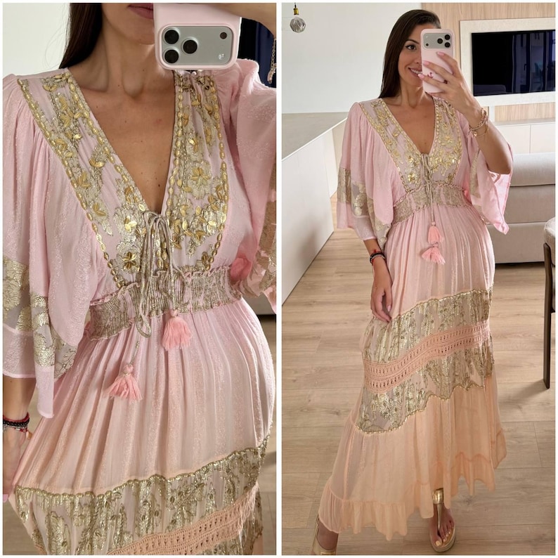 Pu&ograve; includere: Un abito lungo rosa chiaro con profondo scollo a V impreziosito da ricami metallici dorati, maniche ampie e vita arricciata. La gonna presenta fasce orizzontali in tessuto metallico dorato, dettagli in pizzo e un orlo con volant.