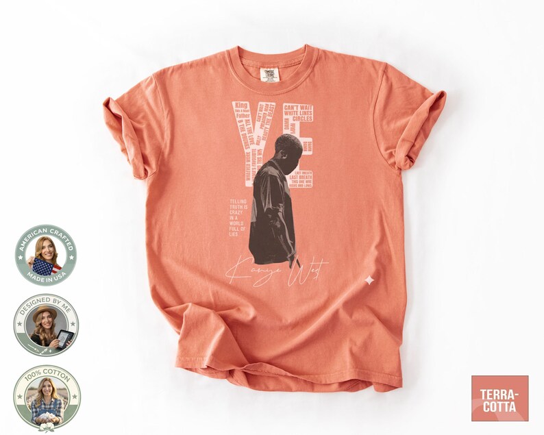 May include: Terracotta-colored t-shirt featuring a black and white image of a person and the name "Kanye West" in a handwritten font. The shirt also has the words "VE" and other text in a white font. The shirt is made of 100% cotton.