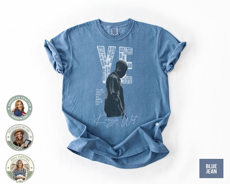 May include: Blue jean-colored t-shirt featuring a black and white image of a person. The word "YE" is printed in white, along with other text. The shirt also has the words "Kanye West" in a cursive font.