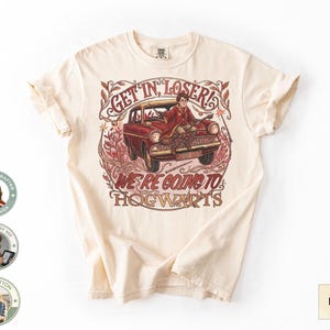 May include: Ivory-colored t-shirt featuring a vintage car with a person in it, and the text "GET IN, LOSER! WE'RE GOING TO HOGWARTS." The design is in shades of red and brown. The shirt is made of 100% cotton.