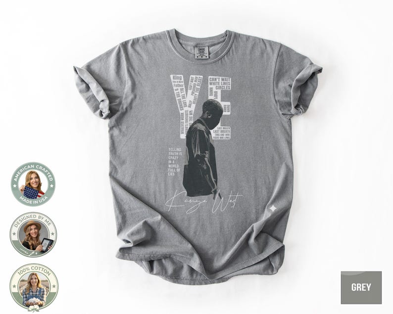 May include: A gray t-shirt featuring a graphic of a person and the word "YE" in white. The shirt includes text and the signature "Kanye West". The shirt is made of 100% cotton.