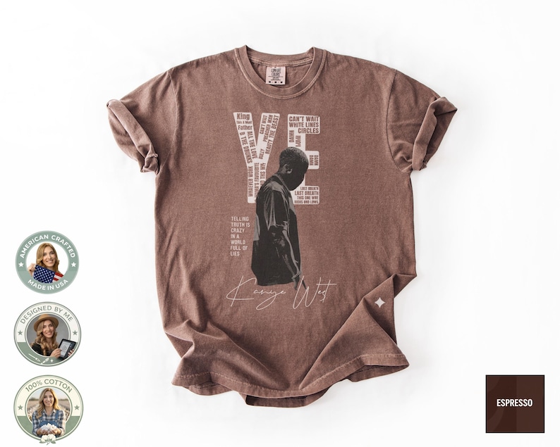 May include: Espresso-colored t-shirt featuring a black and white graphic of a person and the name "Kanye West" in a cursive font. The shirt includes text elements such as "YE" and "CAN'T WAIT WHITE LINES CIRCLES". The shirt is made of 100% cotton.