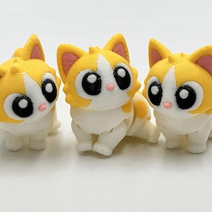 Peut inclure: Trois petites figurines de chat articul&eacute;es en plastique jaune et blanc. Chaque chat pr&eacute;sente de grands yeux noirs avec des reflets blancs, l'int&eacute;rieur des oreilles rose et un petit nez rose. Les figurines ont une finition textur&eacute;e.