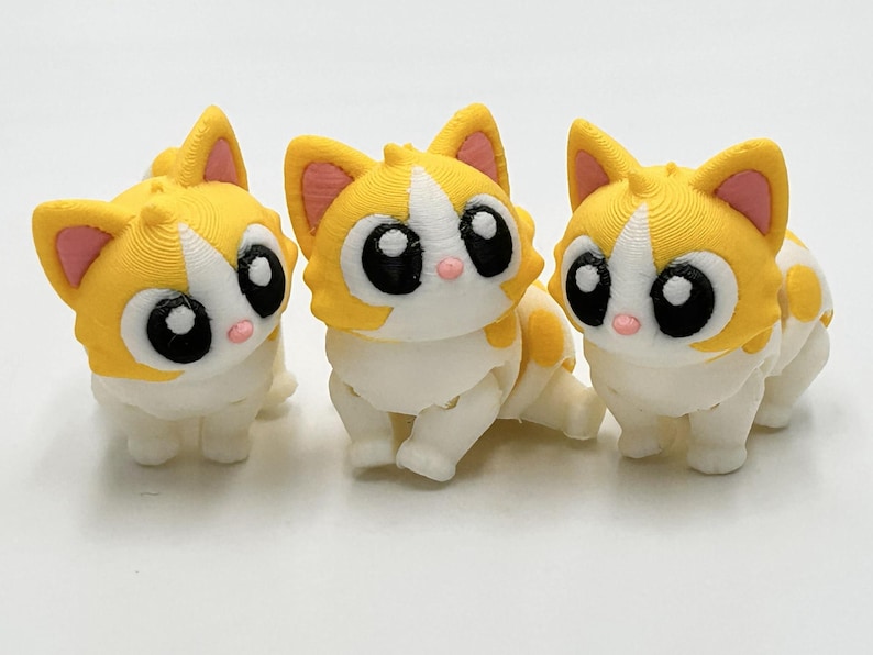 Peut inclure: Trois petites figurines de chat articul&eacute;es en plastique jaune et blanc. Chaque chat pr&eacute;sente de grands yeux noirs avec des reflets blancs, l'int&eacute;rieur des oreilles rose et un petit nez rose. Les figurines ont une finition textur&eacute;e.