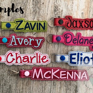 Puede incluir: Seis llaveros personalizados con diferentes nombres bordados en ellos. Los llaveros est&aacute;n hechos de tela y tienen un peque&ntilde;o c&iacute;rculo de tela de color contrastante en la parte superior. Los nombres son: Zavin, Jaxson, Avery, Delaney, Charlie y McKenna.