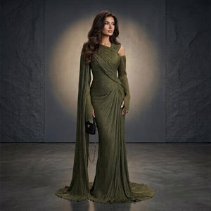 Peut inclure: Une robe longue vert olive avec une texture plissée, une encolure asymétrique et de longues manches fluides qui tombent jusqu'au sol. La robe présente un corsage ajusté avec un drapé diagonal et un petit sac à main noir à bandoulière.