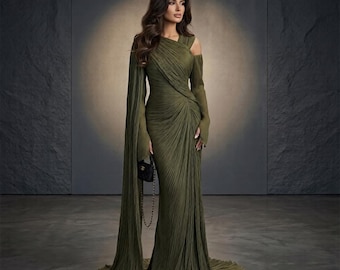 May include: A floor-length olive green gown featuring a pleated texture, an asymmetrical neckline, and long, flowing sleeves that extend to the floor. The dress has a fitted bodice with diagonal draping and a small black handbag with a chain strap.