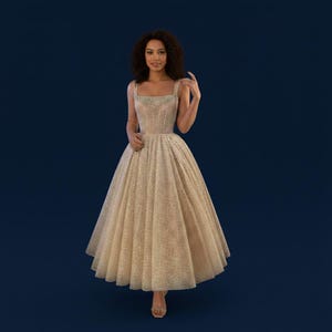 May include: A sparkling, knee-length formal dress in a champagne color. The dress features a fitted bodice with square neckline and thin straps, and a full, flared skirt. The fabric is covered in shimmering sequins, creating a glamorous look.