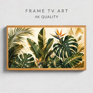 Op de afbeelding: Een ingelijste botanische print met weelderige groene tropische bladeren en oranje bloemen. Het kunstwerk staat tegen een crèmekleurige achtergrond en is ingelijst in een lichtbruine houten lijst. Tekst bovenaan luidt "FRAME TV ART" en "4K QUALITY".