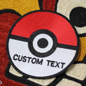 May include: Embroidered patch in the style of a Poké Ball, featuring red and white sections with a black border and center circle. The text "CUSTOM TEXT" is displayed on the white section. The patch is on a textured background.