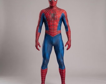 May include: A full-body spandex costume featuring a red and blue color scheme with a black spider emblem on the chest. The suit includes a matching mask with white eye lenses and a black web pattern printed across the red sections of the fabric.