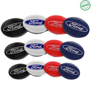 Op de afbeelding: Een verzameling van negen Ford-embleem naafdoppen in verschillende kleuren. De doppen zijn zwart, wit, rood en blauw, elk met het Ford-logo in zilver. De doppen zijn handgemaakt.