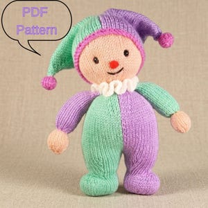 May include: A knitted jester doll with a smiling face, wearing a two-toned outfit of green and purple. The doll has a ruffled collar, a pointed hat with pom-poms, and the text "PDF Pattern" in a speech bubble.