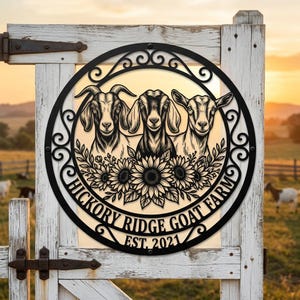 Könnte beinhalten: Ein rundes schwarzes Metallschild mit einem Scherenschnitt-Design von drei Ziegen über einer Gruppe von Sonnenblumen. Der Text HICKORY RIDGE GOAT FARM und EST. 2021 ist entlang der unteren Kurve des Rahmens mit dekorativen Schnörkeln eingraviert.