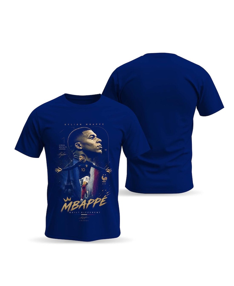 May include: A royal blue short-sleeved t-shirt featuring a graphic print of Kylian Mbapp&eacute;. The design includes a portrait, a full-body action shot, the text "MBAPP&Eacute;" in gold, "BUILT DIFFERENT" below it, and the Eiffel Tower in the background.