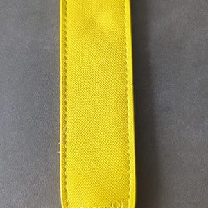 K&ouml;nnte beinhalten: Ein leuchtend gelbes, l&auml;ngliches Stifteetui mit abgerundeter Spitze und einer strukturierten, kreuzschraffierten Oberfl&auml;che. Im unteren Bereich ist der Schriftzug MONTBLANC sowie das markentypische Berggipfel-Logo eingepr&auml;gt.