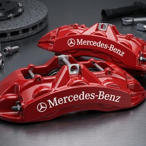 Puede incluir: Dos pinzas de freno de automóvil en color rojo brillante con el logotipo y el texto de Mercedes-Benz en blanco. Estos componentes de alto rendimiento están diseñados con múltiples pistones y puntos de montaje, con un acabado liso.