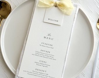Menú de boda con lazo de cinta, tarjeta de menú personalizada, mantelería y decoración de mesa de boda.