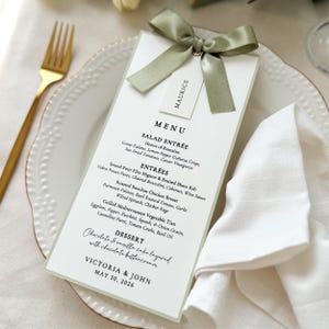 Elegant sage green bordered wedding menu card with satin ribbon bow and place card for a refined table setting