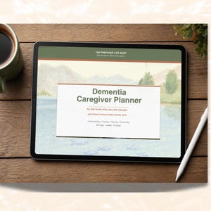 May include: A digital tablet displays a "Dementia Caregiver Planner" with a landscape background. The tablet is on a wooden surface, next to a cup of coffee, a white stylus, and a small plant. The planner's text includes "Understanding, Tracking, Planning, Connecting."