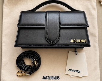 Bolso mini de mano Jacquemus Le Bambino de piel negra con asa superior y bandolera con logo dorado.