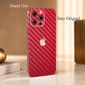 May include: Red carbon fiber textured phone case with the Apple logo. The case has a diagonal weave pattern and covers the back and sides of the phone. Text on the image reads "Stand Out" and "Stay Original".