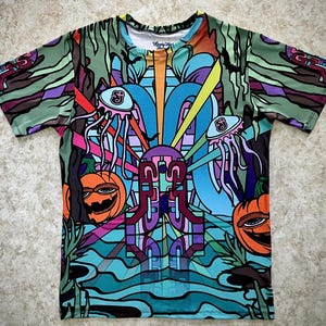 May include: A short-sleeve t-shirt featuring an all-over graphic print with vibrant colors including orange, purple, blue, and green. The design displays two jack-o'-lanterns, two jellyfish-like creatures, and abstract geometric patterns.