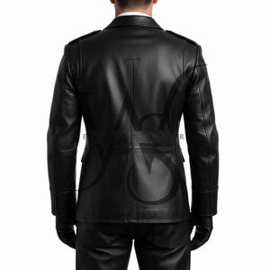 May include: A black leather jacket with a tailored fit, featuring a notched collar, shoulder epaulets, and a double-breasted design. The jacket has two front pockets and is worn with black gloves and pants. The back of the jacket has vertical seams.