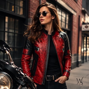 May include: A red and black leather motorcycle jacket with a zip-up front. The jacket has black panels on the shoulders and sleeves. The person is wearing black sunglasses and black trousers. A motorcycle is partially visible.