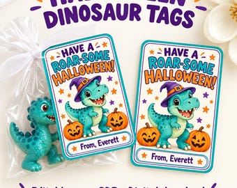 Może przedstawiać: Dwie prostokątne zawieszki halloweenowe z turkusowymi dinozaurami w fioletowych kapeluszach czarownic, pomarańczowymi dyniami oraz napisem 'HAVE A ROAR-SOME HALLOWEEN!' i 'From, Everett'. Jedna zawieszka znajduje się w plastikowej torebce.