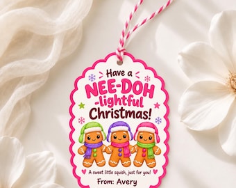 May include: A scalloped oval gift tag with a pink border and white background. It features three gingerbread characters wearing colorful winter hats and scarves. The text reads: Have a NEE-DOH-lightful Christmas! A sweet little squish, just for you! From: Avery.