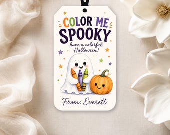 Może przedstawiać: Prostokątna biała zawieszka prezentowa z czarną wstążką, zawierająca napis COLOR ME SPOOKY have a colorful Halloween! oraz From: Everett. Wzór przedstawia białego duszka trzymającego trzy kredki obok uśmiechniętej pomarańczowej dyni.