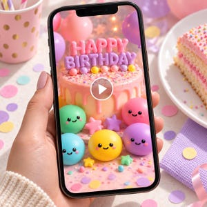 May include: A smartphone screen displaying a digital graphic of a pink birthday cake with the text HAPPY BIRTHDAY in pink letters, surrounded by colorful smiling spheres and stars, with a white play button icon centered on the screen.