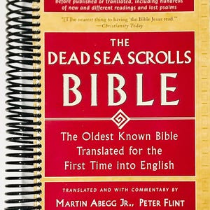 Puede incluir: Un libro titulado "The Dead Sea Scrolls Bible" con una cubierta roja y texto blanco. El libro está encuadernado en espiral y presenta texto sobre la Biblia más antigua conocida traducida al inglés.