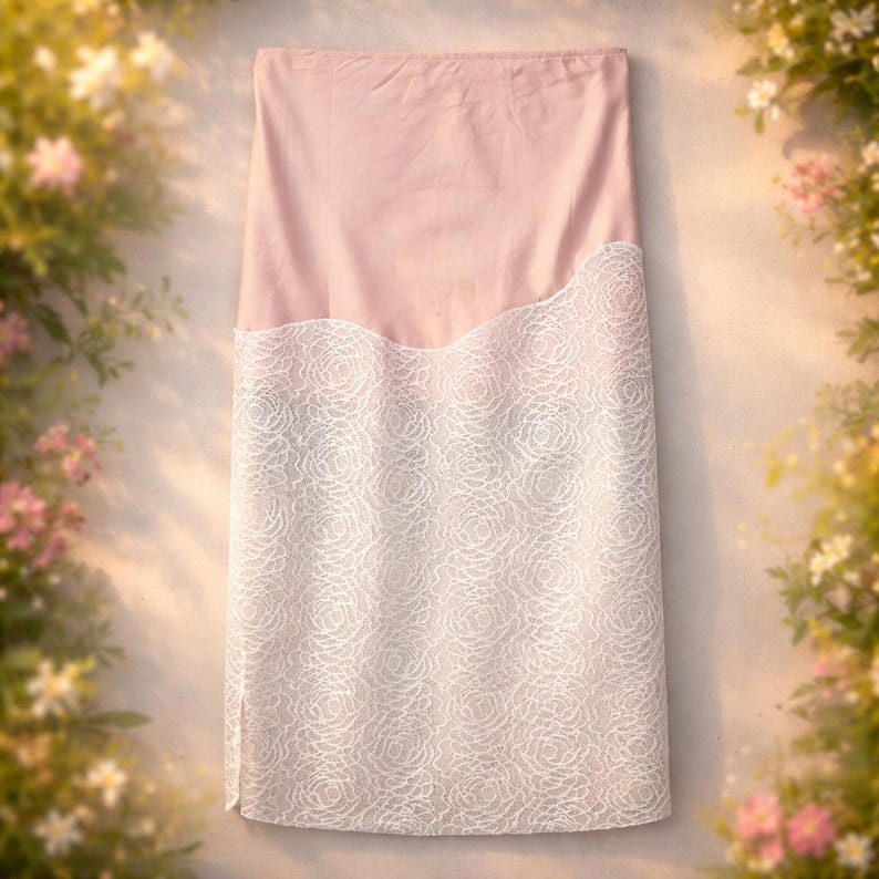 May include: A light pink skirt with a white lace overlay. The lace features a floral pattern and covers the lower portion of the skirt. The top section is a solid light pink fabric. The skirt is displayed against a neutral background.