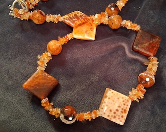 Grandes cuentas triangulares de ágata cornalina con aspecto de piel de serpiente, con detalles redondos y pequeños fragmentos.